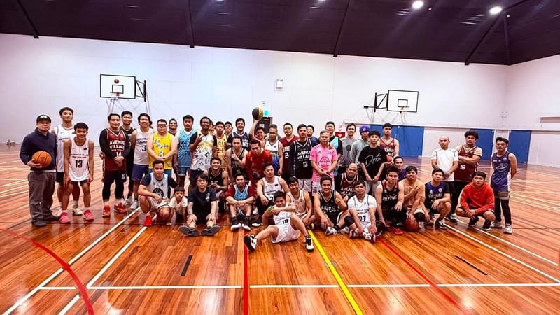 A group of players in basketball jerseys posing together on an indoor court
