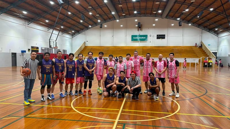 Players and referees in team jerseys posing on an indoor basketball court